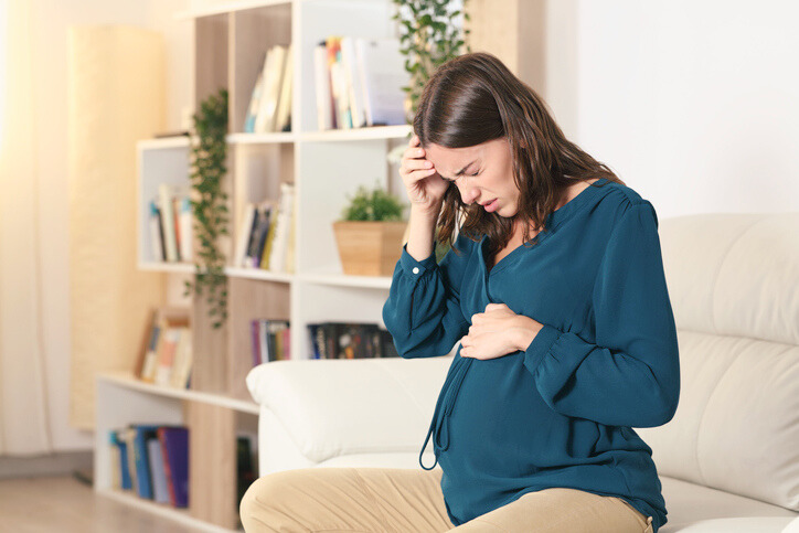 Pregnant woman suffering headache complaining at home