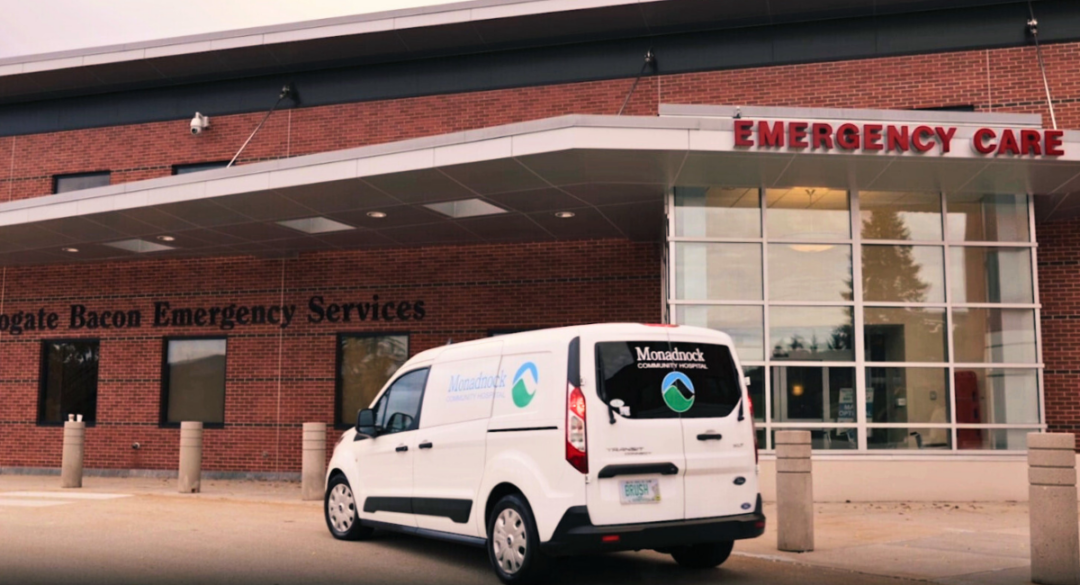 Monadnock Community Hospital van parked in front of the Emergency Care entrance of the hospital building, showcasing the Monadnock Community Hospital logo