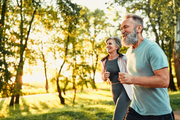 Middle-aged couple jogging on a sunlit path outdoors representing improved mobility and active living after orthopedic care