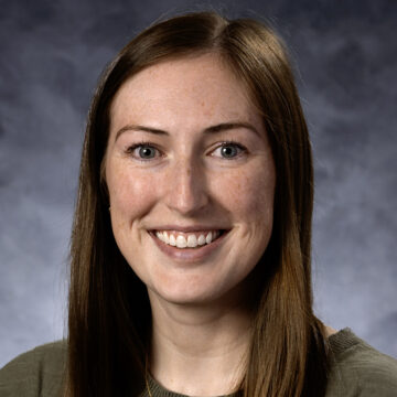 A professional portrait of Morgan Jenkins, an occupational therapist with long, straight brown hair, smiling brightly. She is dressed in a professional top and stands against a neutral background.