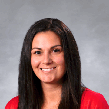 A professional portrait of Chelsie Fukuda, a physical therapist with long, straight, dark brown hair, smiling warmly. She is wearing a bright red top against a soft, neutral-colored background.