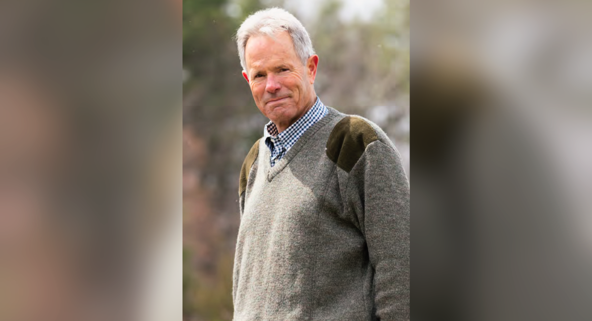 Randall Martin wearing a green sweater and checkered shirt, stands outdoors with a gentle smile, showing his appreciation for the care received at Monadnock Community Hospital.