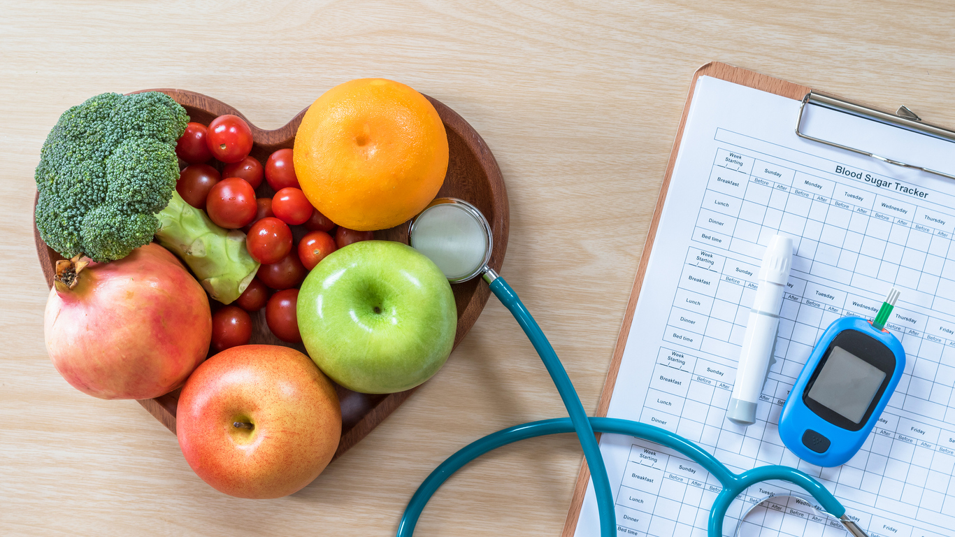 Health and wellness seminars heart shaped bowl of fruit next to medical chart and stethoscope