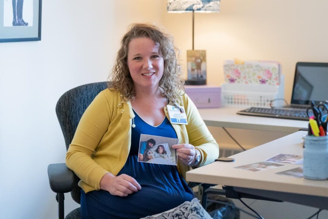 Jackie in her current office holding a photo of her parents holding her and her twin brother the day they were born in the same room Photo credit Mikayla Feehan