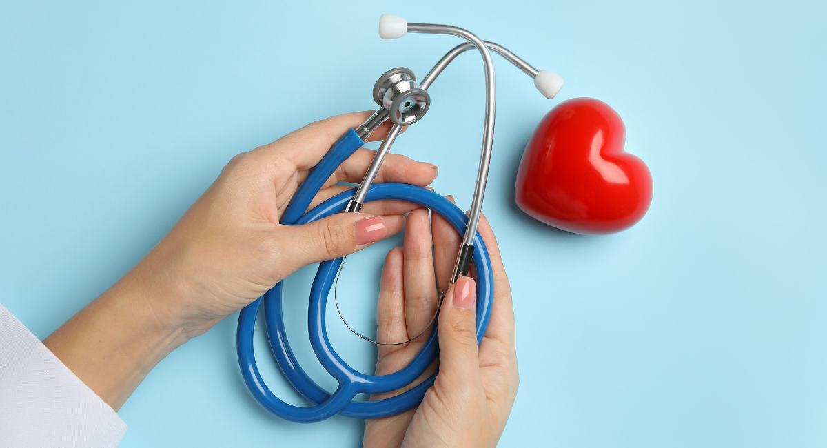 Person in scrubs holding stethoscope with red heart