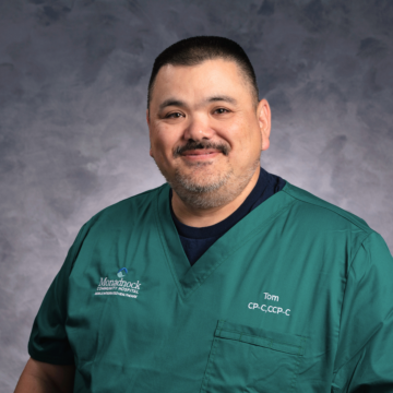 Thomas Dardas, Community Paramedic at Monadnock Community Hospital, wearing green scrubs and smiling in a professional portrait