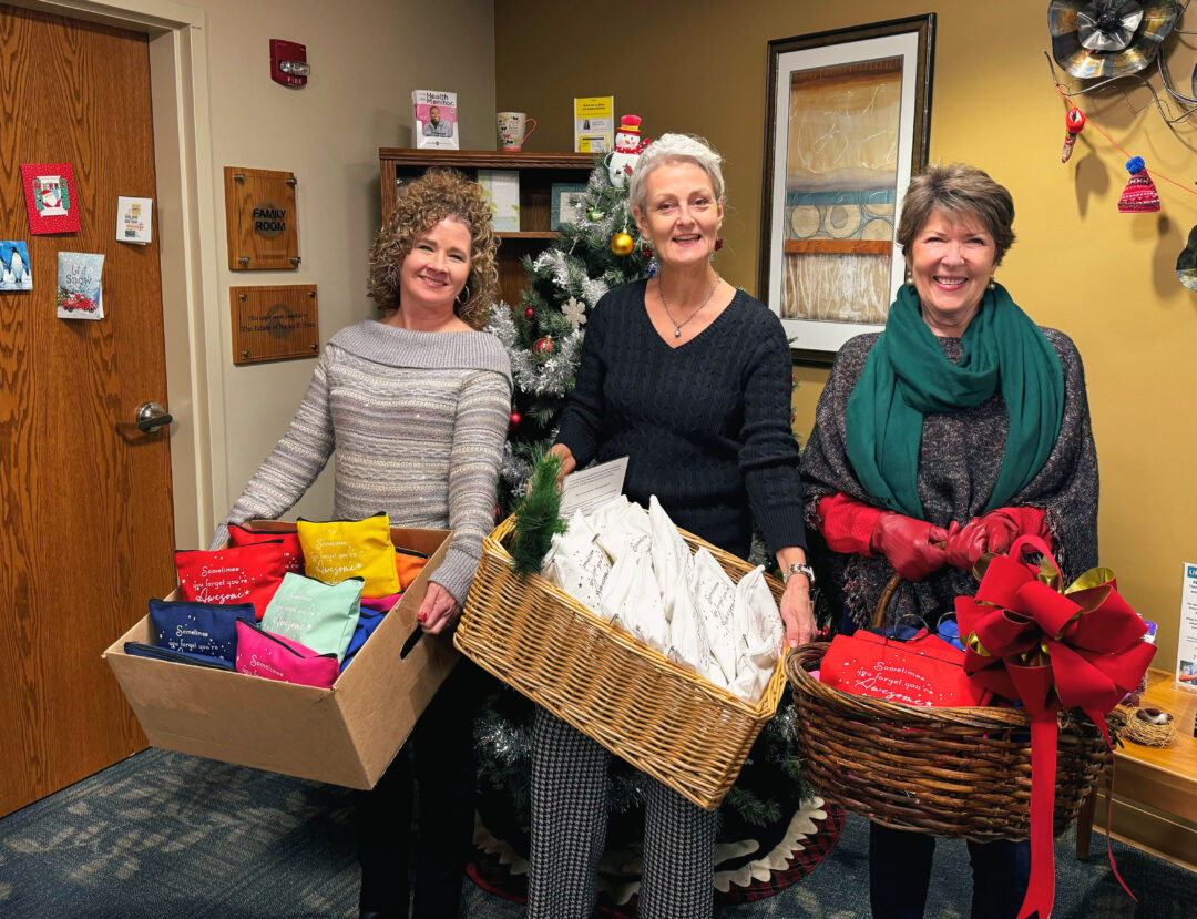 Pictured from left to right: Denise Chatel, Ellen Smith, and Ruth Clark smile bright as they donate gift bags for Oncology patients