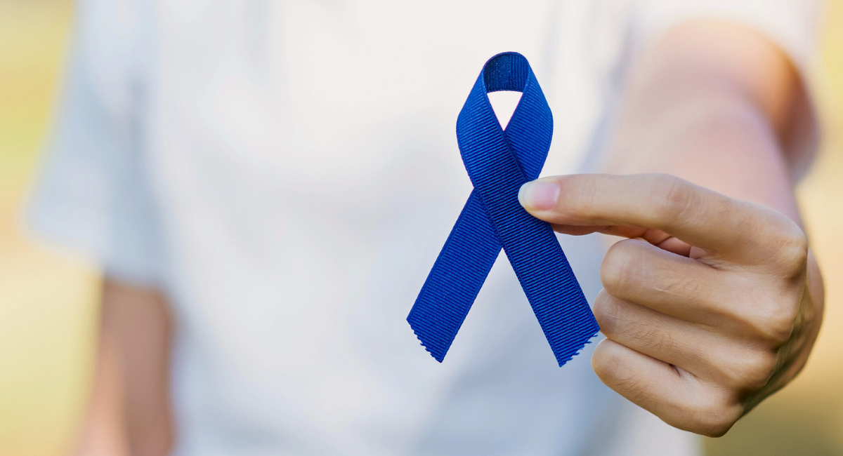 Hand holding a dark blue ribbon symbolizing support and awareness, with a soft, blurred background