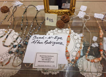 Glass display case holds handmade necklaces by Afton Rodriguez