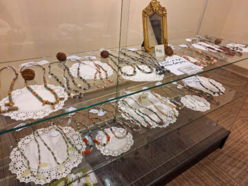 Glass display case holds handmade jewelry on doilies
