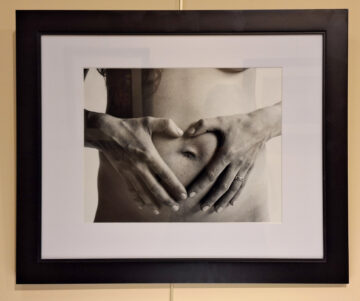 Black and white photo nude person's stomach with hands in front in the shape of a heart