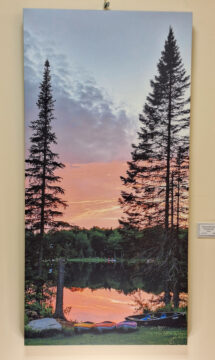 Photo on canvas yellow orange and purple kayaks and canoe pulled up at the bottom orange and pink sunset reflected in lake with forest around with one canoe in the water