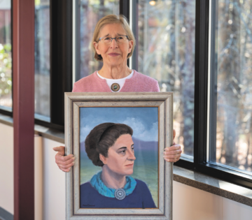 Karen Clement holding a painting of her grandmother, Margaret Adams Clement