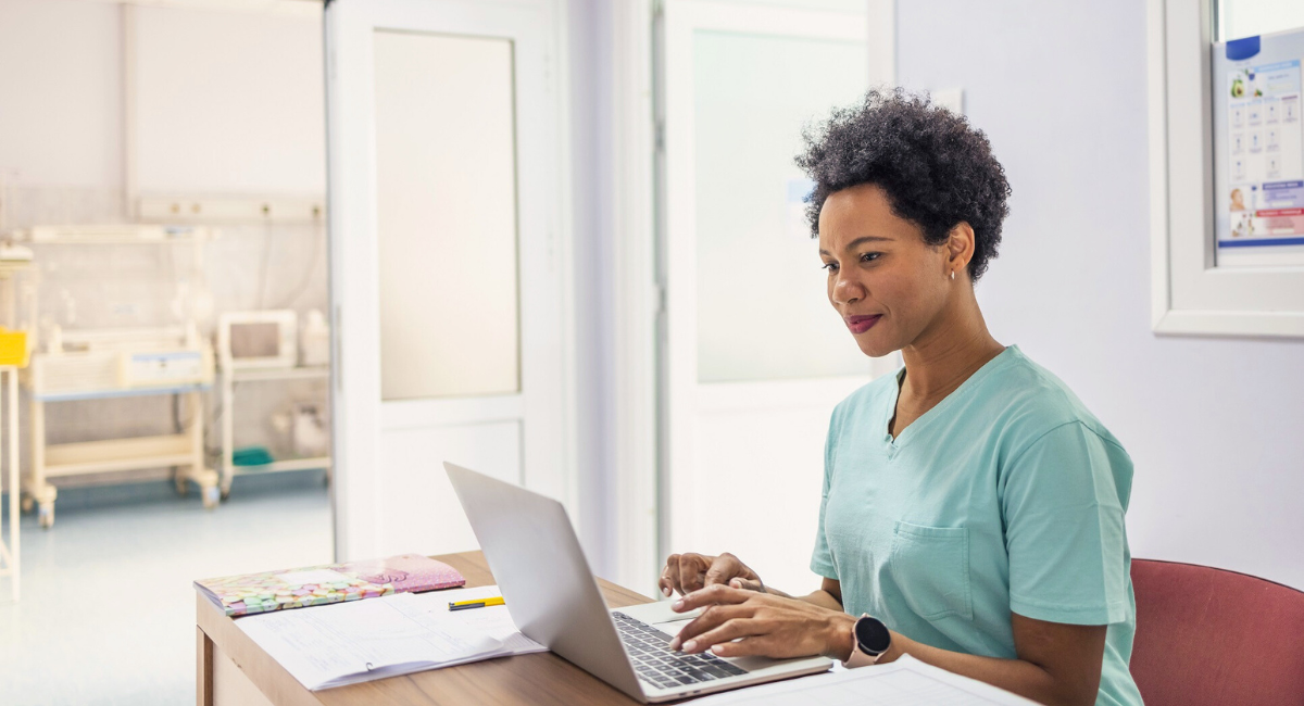 FollowMyHealth Professional Smiling Black Female Head Nurse or Doctor Uses Medical Computer