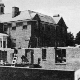 A historical black-and-white photo showing the construction of Monadnock Community Hospital in 1949, with workers building the structure and scaffolding around the site.