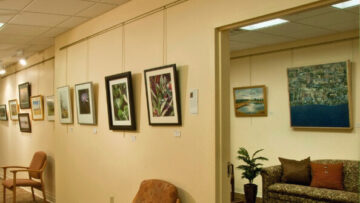 An interior view of the Healing Arts Gallery at Monadnock Community Hospital, featuring framed artwork hanging on the walls and a cozy seating area.