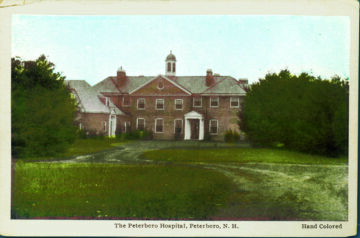 A hand-colored vintage photograph of The Peterboro Hospital in Peterboro, New Hampshire. The building is a two-story brick structure with a symmetrical facade, featuring a central entrance with a white portico and cupola on the roof. The hospital is surrounded by a grassy area and trees. The photo has a nostalgic feel, highlighting the hospital's historical significance.