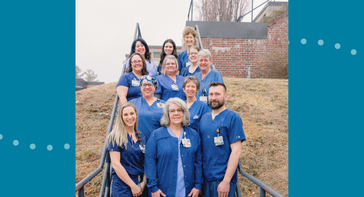 A group of twelve healthcare professionals in blue scrubs and work attire, standing on an outdoor staircase. They are smiling and looking at the camera, showcasing the collaborative and friendly team at Monadnock Community Hospital