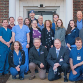 A large group of doctors, nurses, and staff members standing together outside of the Monadnock Community Hospital building.