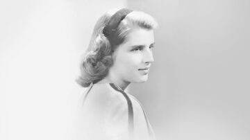 A black-and-white portrait of a woman with light-colored hair, wearing a headband and looking to the side.