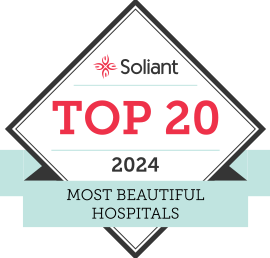 A badge with a diamond shape and a light blue ribbon at the bottom. The text reads: "Soliant TOP 20 2024 Most Beautiful Hospitals." The word "Soliant" is at the top, with a small red flower logo above it.