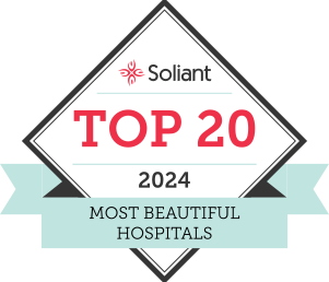 A badge with a diamond shape and a light blue ribbon at the bottom. The text reads: "Soliant TOP 20 2024 Most Beautiful Hospitals." The word "Soliant" is at the top, with a small red flower logo above it.