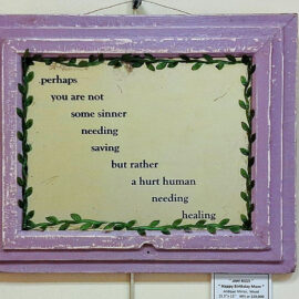 A framed piece titled 'Happy Birthday Mom' by Jam Rizzi, featuring a poetic text within a rustic purple frame. The text, surrounded by a border of leaves, reads: '.perhaps you are not some sinner needing saving but rather a hurt human needing healing