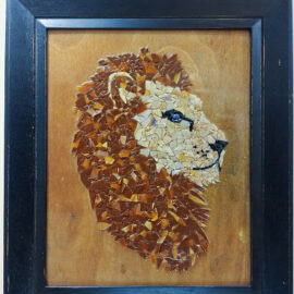 A framed mosaic artwork by Jennifer A. Vallauri depicting a lion's profile, crafted with small pieces of brown and beige ceramic tiles. The lion's mane is intricately detailed, creating a textured and vibrant representation against a wooden background within a black frame