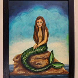 A framed painting of a mermaid sitting on a rock surrounded by water. She has long brown hair and a green, scaly tail, with a blue sky and clouds in the background