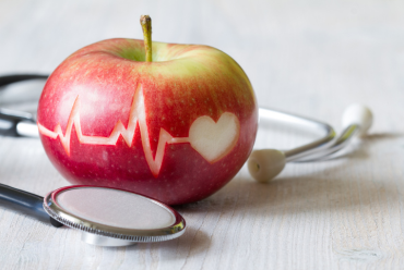 An apple with a heartbeat symbol, representing heart health as part of the comprehensive cardiology services in Peterborough, N