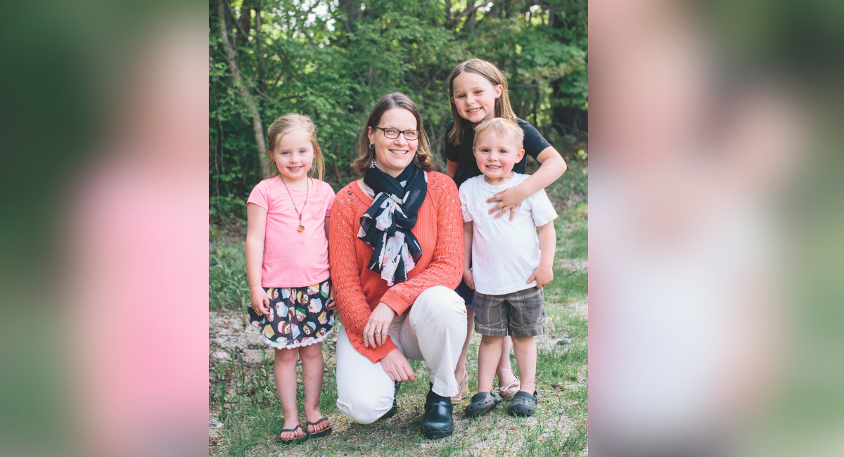 Carrie Klonel, DO, of Antrim Medical Group, smiling with Isabelle, Abigail, and Levi Hardwick, three young children outdoors