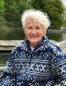  warm portrait of Phyllis Scott, a beloved community member and benefactor, smiling gently with a garden backdrop, honoring her legacy of generosity and love for the community.