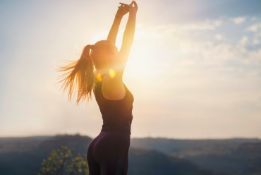 A woman stretching in the sunlight, symbolizing the importance of access to pain management specialists for a healthier lifestyle in Peterborough, NH