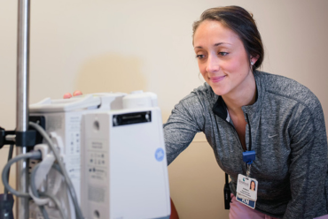 A healthcare professional smiling while working with a machine, representing primary care services at Monadnock Community Hospital