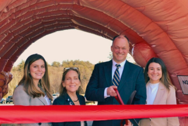 The grand opening of the gastroenterology offices with several professionals cutting the ribbon under a giant inflatable colon