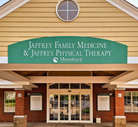 The entrance to Jaffrey Family Medicine & Jaffrey Physical Therapy features a wide green awning with the practice's name and the Monadnock Community Hospital logo. The brick building has large glass doors and a welcoming appearance