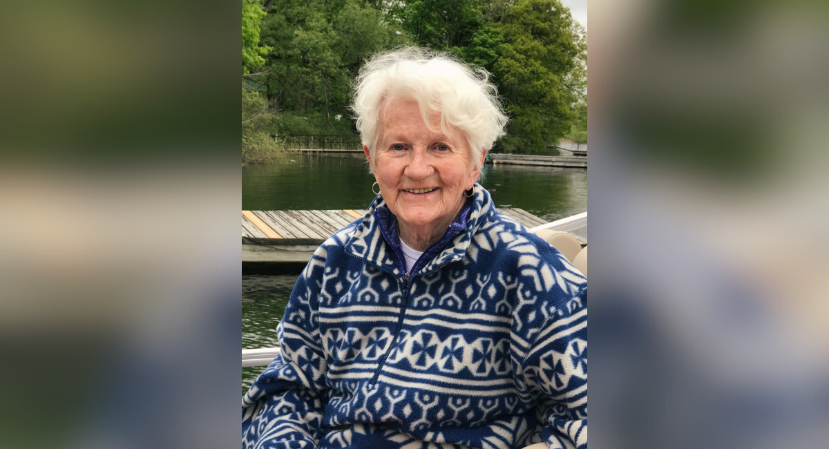 A warm portrait of Phyllis Scott, a beloved community member and benefactor, smiling gently with a lake backdrop, honoring her legacy of generosity and love for the community.