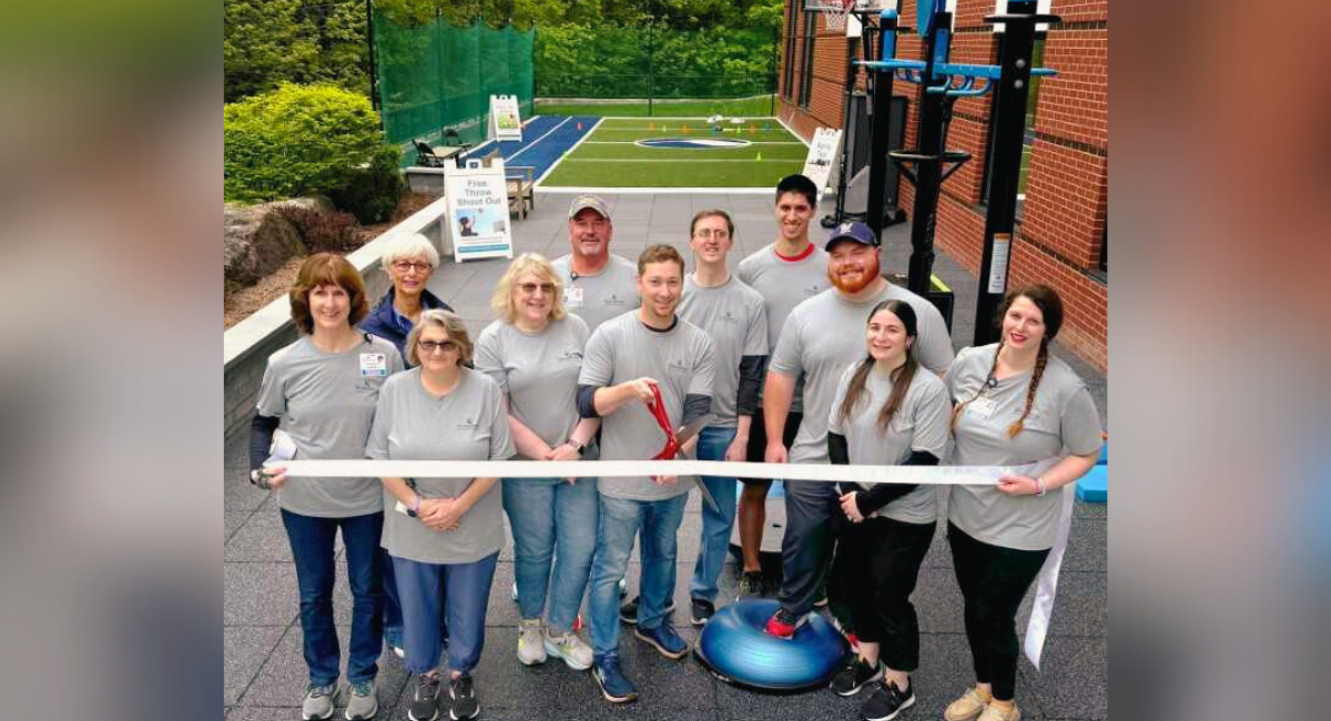 Group photo of Monadnock Community Hospital staff at the ribbon-cutting ceremony for the new outdoor rehabilitation space, featuring exercise stations and a sports turf area