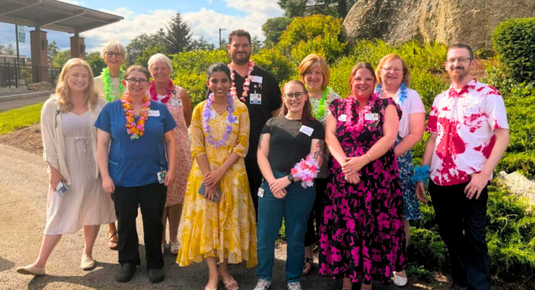 A group photo of Monadnock Community Hospital staff members standing together outside the hospital, smiling and showcasing a diverse team committed to providing exceptional care.