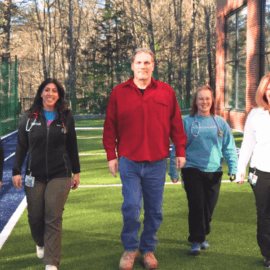 Bruce walks confidently alongside Monadnock Community Hospital's Pulmonary Rehab team on a sunny outdoor track, showcasing the transformative impact of the program.