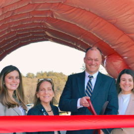 Four team members smiling during a ribbon-cutting ceremony inside a life-sized inflatable colon model, symbolizing community health awareness and education at Monadnock Community Hospital