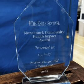 Close-up of a clear glass award presented by The Keene Sentinel to Monadnock Community Hospital's Mobile Integrated Healthcare department for the 2024 Health Impact Award