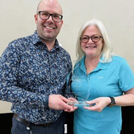 Joshua Patrick and Karen Bednarski of Monadnock Community Hospital smiling while holding the Monadnock Community Health Impact Award at the Keene Family YMCA during the "For the Health of It!" community health fair