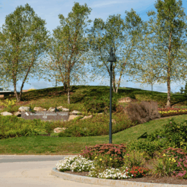 A landscaped rotary featuring a hill with birch trees, colorful flowers, and the Monadnock Community Hospital sign in front of a blue sky.