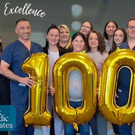 Dr. Vache Hambardzumyan, Orthopedic Physician Assistant Thomas Quinn, and the Monadnock Orthopaedic Associates team stand together holding large gold balloons forming the number '100.' The image celebrates the milestone of 100 spine surgeries. The background features a blurred hospital setting, with the words 'Celebrating Excellence' written in white script at the top and the Monadnock Orthopaedic Associates logo in the bottom left corner