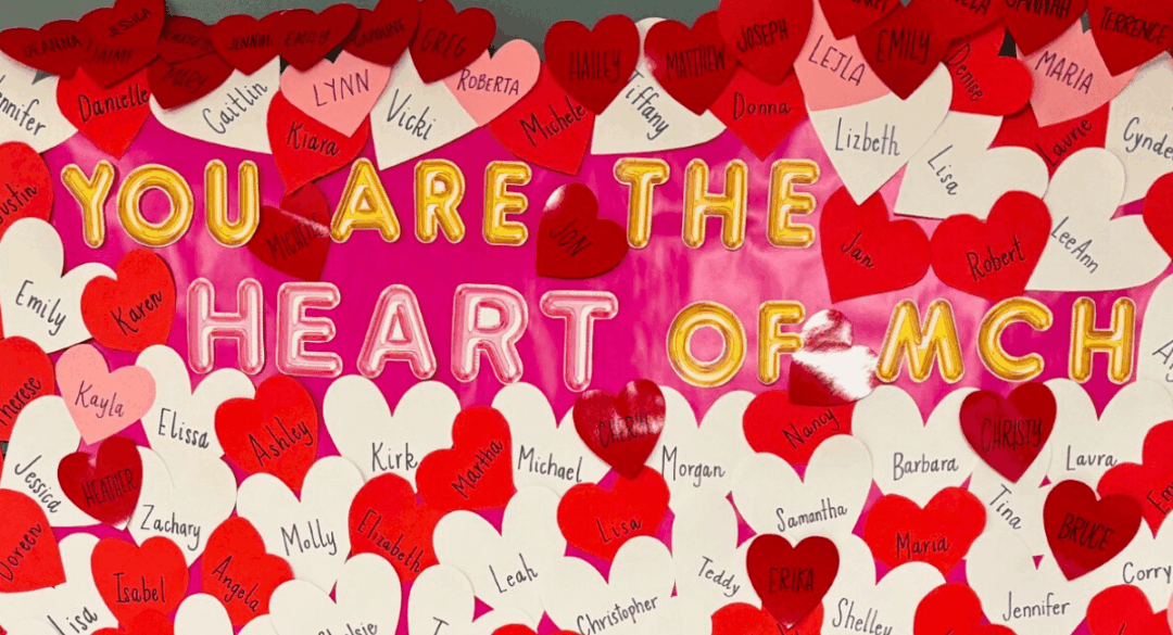 A vibrant appreciation display at Monadnock Community Hospital featuring the message "You Are the Heart of MCH" in bold letters, surrounded by red and white heart-shaped cutouts with employee names written on them.