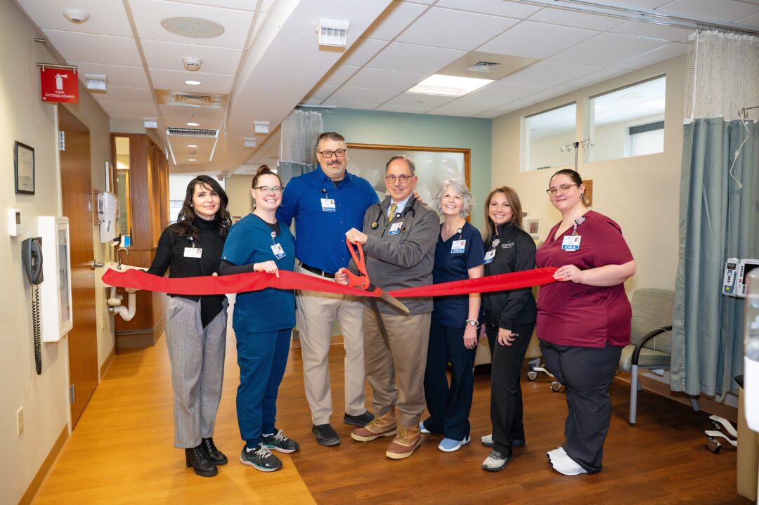 Dr. Jonathan Krant and the Monadnock Rheumatology Associates care team celebrate the ribbon cutting of their newly opened space at Monadnock Community Hospital’s Oncology and Infusion Therapy Center. The group stands smiling in a clinical setting, holding a large ceremonial red ribbon and scissors, marking the start of a new era of specialized rheumatologic care in the region.