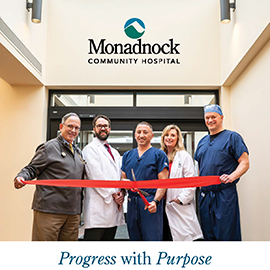 Five Monadnock Community Hospital staff members stand together smiling as they cut a ceremonial red ribbon inside a bright hospital corridor. A skylight and the Monadnock Community Hospital logo are visible above them. The caption below reads, “Progress with Purpose – 2025 Report to Our Community.”