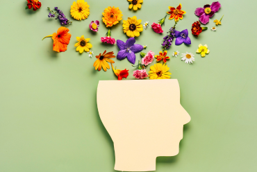 An illustration of a human head with flowers growing from it, symbolizing mental health, growth, and well-being