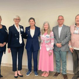 U.S. Rep. Maggie Goodlander stands with Monadnock Community Hospital leadership and staff during a discussion on Medicaid and Medicare cuts, smiling together in a meeting room.